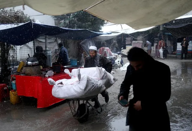 An Afghan man pushes his wheelbarrow in a market during a snowfall in Kabul, Afghanistan, January 3, 2022. (Photo by Ali Khara/Reuters)