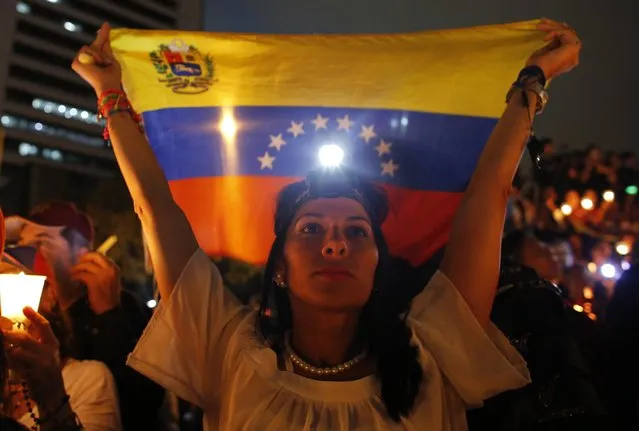 A demonstrator holds a Venezuelan flag during a vigil for the victims of the clashes with the government's security forces, during protest against President Nicolas Maduro in Caracas, Venezuela, Wednesday, May 17, 2017. Several humanitarian organizations and the opposition have accused the security forces of using too much violence during demonstrations against the government, which have left dozens dead. (Photo by Ariana Cubillos/AP Photo)