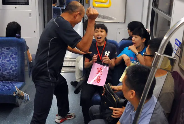 An “attacker” (L) threatens “passengers” inside a train carriage as they participate in an anti-attack drill conducted by railway officials in New Taipei City on June 12, 2014. This drill was conducted after a 21-year-old man in May attacked passengers on a subway train, killing four and wounding two dozen others, in a terrifying rampage that shocked a place otherwise proud of its low violent crime levels. (Photo by Mandy Cheng/AFP Photo)