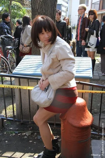 A Japanese woman sits on a large wooden phallic sculpture, as part of the Kanamara festival (Festival of the Steel Phallus), in the grounds of Wakamiya Hachimangu shrine, on April 1, 2012 in Kawasaki, Japan