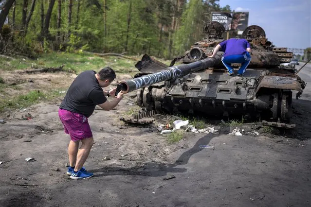 A man takes photos of a destroyed Russian tank, on the outskirts of Kyiv, Ukraine, Sunday, May 8, 2022. (Photo by Emilio Morenatti/AP Photo)