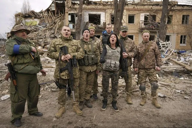Ukrainian servicemen sing a patriotic song with buildings in the background that were destroyed during fighting between Ukrainian and Russian forces in Borodyanka, Ukraine, Tuesday, April 5, 2022. (Photo by Vadim Ghirda/AP Photo)