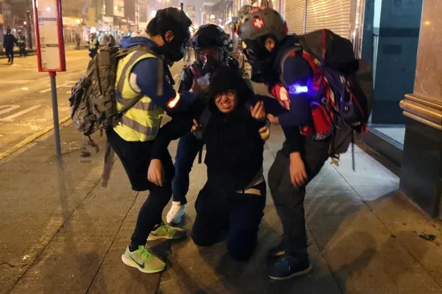 An anti-government demonstrator is helped by medics after running away from tear gas during a protest on New Year s Eve in Hong Kong, China, January 1, 2020.  Thousands of revelers welcomed in 2020 on neon-lit promenades along the picturesque Victoria Harbour, breaking into pro-democracy chants as the clocks struck midnight after more than half a year of often violent unrest. Authorities had canceled the popular new year fireworks for the first time in a decade, citing security concerns. A “Symphony of Lights” took place instead, involving projections on the city's tallest skyscrapers after the countdown to midnight. (Photo by Lucy Nicholson/Reuters)