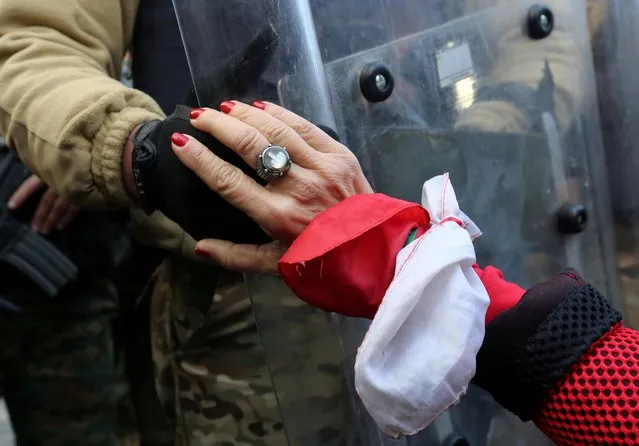 A protestor holds the hand of a Lebanese army soldier during a protest against the political elite in Beirut, Lebanon on January 27, 2020. (Photo by Aziz Taher/Reuters)