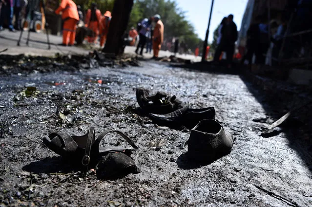 Footwear of victims are seen on the ground as Afghan residents inspect the site of a car bomb attack in western Kabul on July 24, 2017. At least 24 people have been killed and 42 wounded after a car bomb struck a bus carrying government employees in western Kabul on July 24, an official told AFP, the latest attack to strike the Afghan capital. (Photo by Wakil Kohsar/AFP Photo)