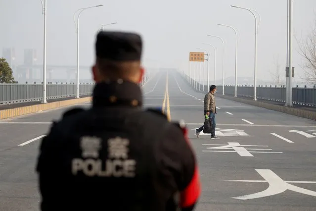 A man arriving from Hubei province approaches a checkpoint at the Jiujiang Yangtze River Bridge in Jiujiang, Jiangxi province, China, January 31, 2020. (Photo by Thomas Peter/Reuters)