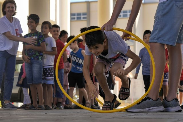 A volunteer of the Russian Cultural Center entertains displaced children at a school in Beirut, Lebanon, Thursday, October 3, 2024, after fleeing the Israeli airstrikes in the south. (Photo by Bilal Hussein/AP Photo)