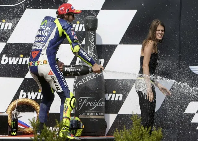 Yamaha MotoGP rider Valentino Rossi of Italy sprays champagne to a grid girl after finishing third in the Czech Grand Prix in Brno, Czech Republic, August 16, 2015. (Photo by David W. Cerny/Reuters)