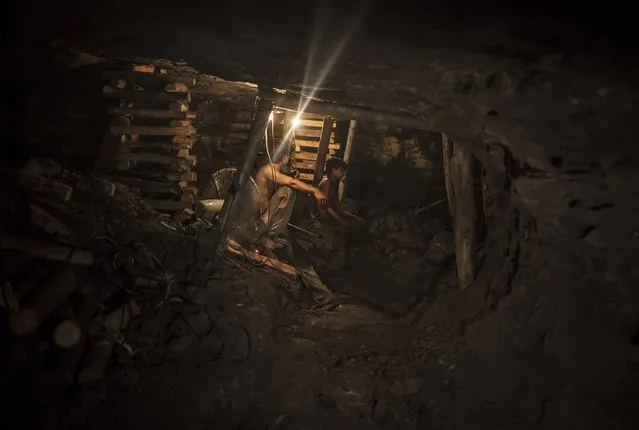 Samiullah, who says he is 14-years-old, sits at the coal face to observe the process of coal mining, underground in Choa Saidan Shah, Punjab province, April 29, 2014. (Photo by Sara Farid/Reuters)