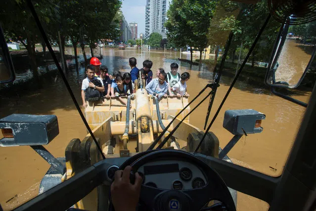People take a excavator on their way to work in Wuhan, Hubei province, July 8, 2016. (Photo by Reuters/Stringer)