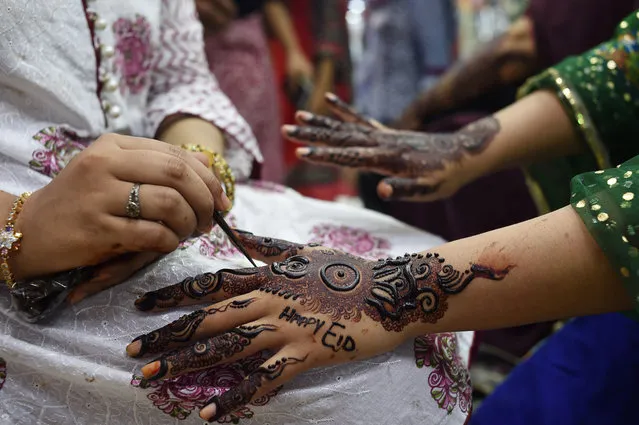 In this picture taken June 23, 2017 a Pakistani Muslim aesthetician applies henna on the hands of a customer, ahead of the Muslim festival of Eid al- Fitr, at a beauty parlor in Karachi The Eid al- Fitr, the biggest festive Muslim event, marks the end of the holy fasting month of Ramadan. (Photo by Asif Hassan/AFP Photo)