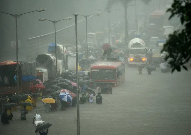 People wade along a flooded street during heavy rain showers in Mumbai on August 29, 2017. Heavy rain brought India's financial capital Mumbai to a virtual standstill on August 29, flooding streets, causing transport chaos and prompting warnings to stay indoors. Dozens of flights and local train services were cancelled as rains lashed the coastal city of nearly 20 million people. (Photo by Punit Paranjpe/AFP Photo)