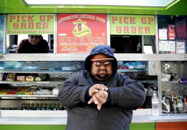 Tacos el Tajin food truck owner Tomas Lopez checks his watch at lunch time in the South Lake Union neighborhood, normally a busy area for Amazon and the biotech industry, as companies like Amazon instructed employees to work from home if they can during the coronavirus disease (COVID-19) outbreak, in Seattle, Washington, U.S. March 18, 2020. (Photo by Jason Redmond/Reuters)