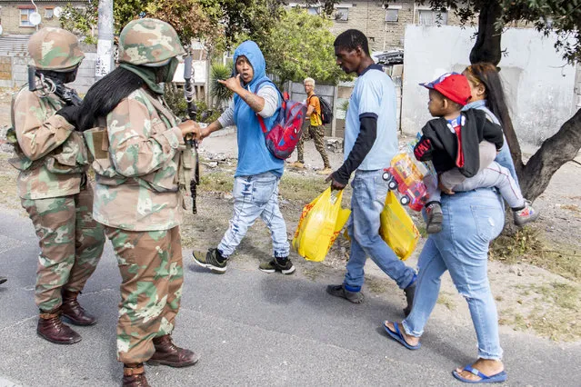 Soldiers interact with resident while on patrol in Mannenburg, Cape Town, South Africa Saturday, March 28, 2020. South Africa went into a nationwide lockdown to restrict public movements for 21 days in an effort to control the spread of the virulent COVID-19 coronavirus.(Photo by AP Photo/Stringer)