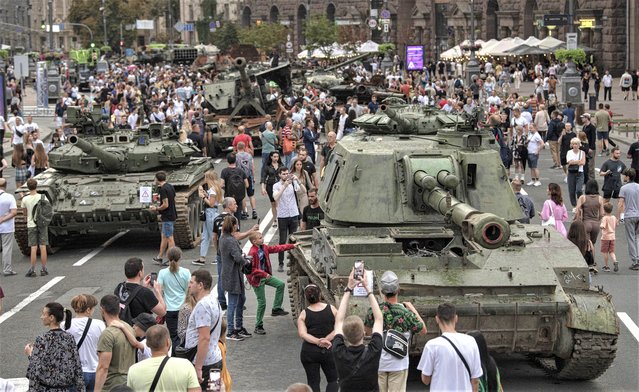 Ukrainians visit an avenue, where destroyed Russian military vehicles have been displayed in Kyiv, Ukraine, Saturday, August 20, 2022. Drawing the attention of large numbers of pedestrians and amateur snappers on Saturday in downtown Kyiv a large column of burned out and captured Russian tanks and infantry carriers were displayed on the central Khreshchatyk boulevard. (Photo by Andrew Kravchenko/AP Photo)