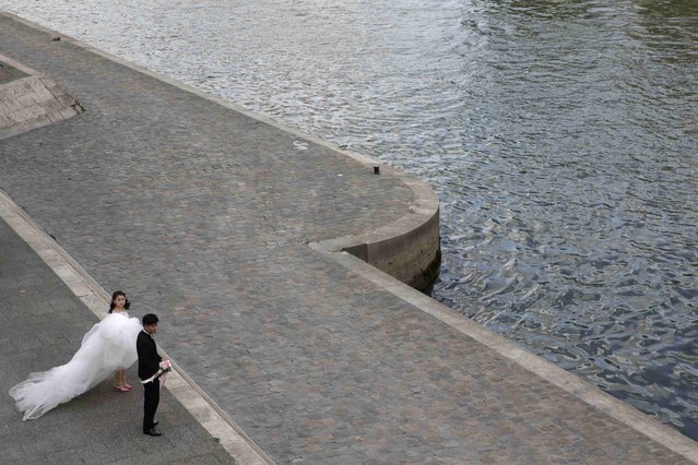 A Chinese couple gets ready on the bank of the Seine river before a pre-wedding photoshoot near the Notre-Dame Cathedral in Paris, France, August 28, 2015. (Photo by Philippe Wojazer/Reuters)
