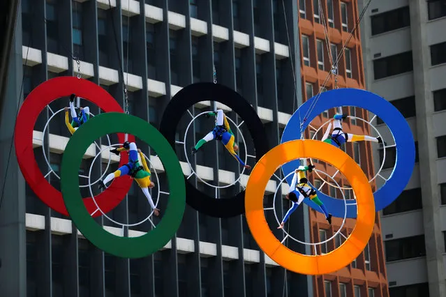 Acrobats perform on the Olympics rings at Paulista Avenue in Sao Paulo's financial center, Brazil, July 24, 2016. (Photo by Paulo Whitaker/Reuters)