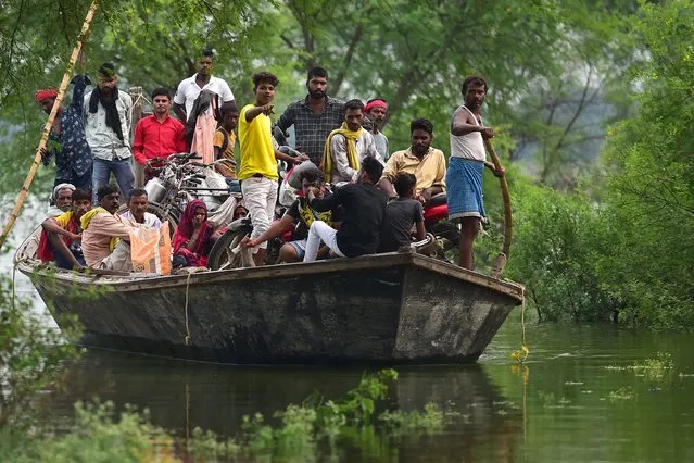 Villagers use a boat to cross a waterlogged road caused by floodwaters after a rise in water levels of rivers Yamuna and Ganges following monsoon rains at Badara Sanuti village near Allahabad on August 24, 2022. (Photo by Sanjay Kanojia/AFP Photo)