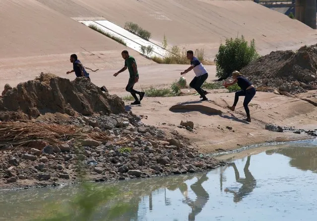 Venezuelan migrants run after crossing the Rio Bravo, or Rio Grande as it is called in the US, into the United States to seek for political asylum, as seen from Ciudad Juarez, Chihuahua State, Mexico, on September 12, 2022. (Photo by Herika Martinez/AFP Photo)