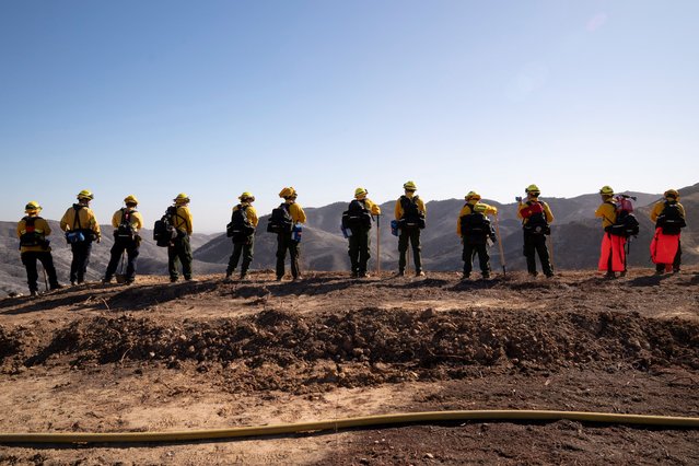 Firefighters from Mexico rest while hiking to their destination to cut a containment line in the Tarzana area during the Palisades Fire in Los Angeles, California, U.S. January 13, 2025. (Photo by David Ryder/Reuters)
