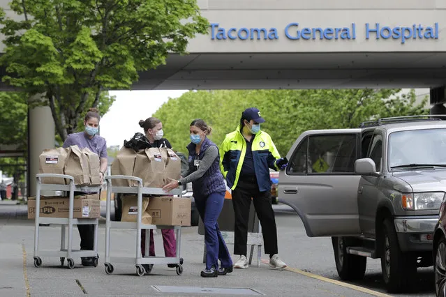 J.D. Elquist, right, of the Downtown Tacoma Partnership, delivers meals to workers at Tacoma General Hospital in Tacoma, Wash., Wednesday, April 29, 2020. The delivery was part of the organization's “Hero Meals” project, which collects donations from the public to purchase meals from restaurants that are then given to healthcare workers, first responders, and other essential workers in the city during the coronavirus outbreak. (Photo by Ted S. Warren/AP Photo)