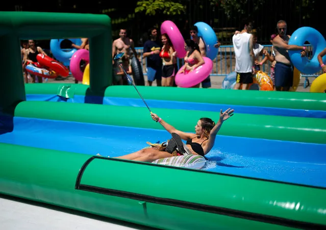 A girl takes a selfie as she slides along a water slide in Madrid, July 24, 2016. (Photo by Javier Barbancho/Reuters)