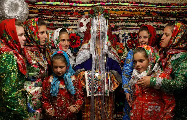 Bulgarian Muslim bride Dhzemile Lilova, 30, poses with friends and relatives in front of the dowry wearing a special make-up called “ghelina” during her wedding ceremony in the village of Draginovo, Bulgaria October 13, 2017. The traditional wedding ritual is held among Pomaks – Slavs who converted to Islam under Ottoman rule. The highlight of the ceremony is the painting of the bride's face, where in a private rite her face is covered in white face cream and decorated with gold flakes and colourful sequins. (Photo by Stoyan Nenov/Reuters)