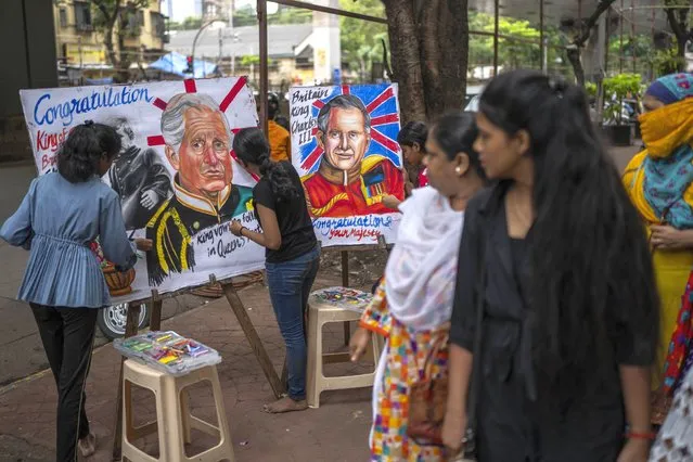 Pedestrians look on as students of Mumbai's Gurukul art school create art works congratulating Britain’s new monarch King Charles III in Mumbai, India, Sunday, September 11, 2022. King Charles III was formally proclaimed sovereign of the United Kingdom on Saturday following the death of his mother, Queen Elizabeth II on Thursday. (Photo by Rafiq Maqbool/AP Photo)