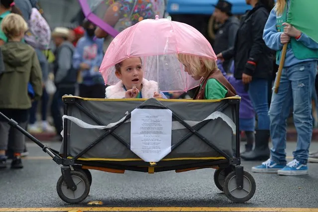Zoe Lopez, 7, left, and Madeline Larsen, 7, of Girl Scout Troop 33895, shield themselves from the rain as they participate during the 27th annual El Sobrante Stroll parade in El Sobrante, Calif., on Sunday, September 18, 2022. (Photo by Jose Carlos Fajardo/Bay Area News Group via AP Photo)