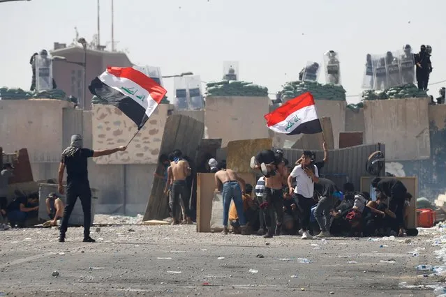 Iraqi anti-government demonstrators clash with security forces during a protest on the Jumhuriya (Republic) bridge leading to the capital Baghdad's high-security Green Zone on October 1, 2022. (Photo by Ahmad Al-rubaye/AFP Photo)