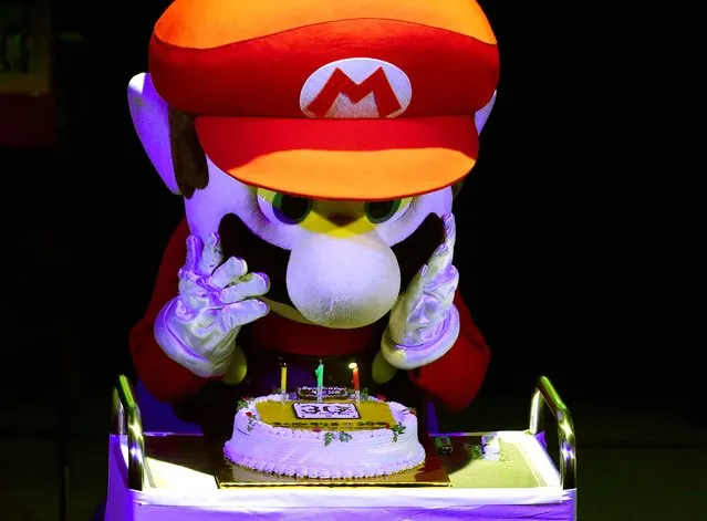 “Super Mario” blows out the candles on a cake during celebrations and a live performance of the most well-known Mario music to mark the game's 30th anniversary in Tokyo on September 13, 2015. Nintendo celebrated the 30th anniversary of Super Mario, one of the best-known characters in video game history, at the event in Tokyo where artists played his theme music to fans dressed up as the hyperactive plumber. (Photo by Toshifumi Kitamura/AFP Photo)