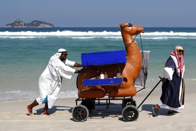 Two beach hawkers dressed as Arab men sell food and drinks from a mock camel in Praia do Pepe Beach of Barra da Tijuca district in Rio de Janeiro, Brazil, 17 August 2016. (Photo by Orlando Barria/EPA)