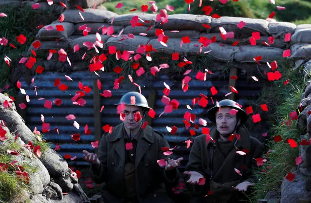 Actors Jake Morgan and Sam Ducane extend their hands to catch poppies, as they pose for photographs at the launch of the 1918 Poppy Pledge in a re-creation of a First World War trench at Pollock House in Glasgow, Scotland November 10, 2017. The actors appeared in the The Wipers Times, a play named after a magazine published by British soldiers in the First World War. (Photo by Russell Cheyne/Reuters)