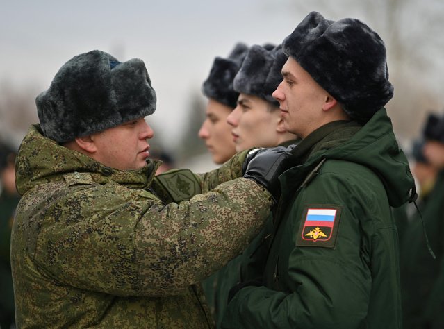 A Russian serviceman adjusts unifirm of a conscript called up for military service during the annual autumn draft at a gathering point before departure for garrisons, in Omsk, Russia on November 10, 2022. (Photo by Alexey Malgavko/Reuters)