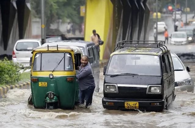 A driver pushes his autorickshaw past a waterlogged street in New Delhi, India, Wednesday, August 31, 2016. Normal life was thrown out of gear as heavy rainfall lashed the city Wednesday morning, resulting in waterlogging and traffic jams. (Photo by Manish Swarup/AP Photo)