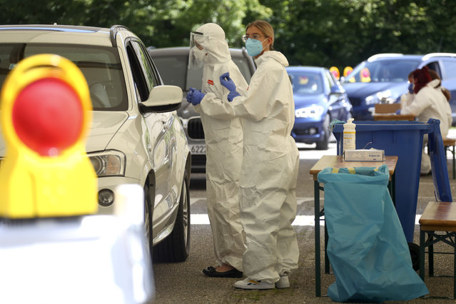 Health workers collect samples at a makeshift COVID-19 testing station in Mamming, Germany, Tuesday July 28, 2020. After a local coronavirus outbreak on the cucumber farm premises, state authorities have quarantined the entire farm and its workers. (Photo by Matthias Schrader/AP Photo)