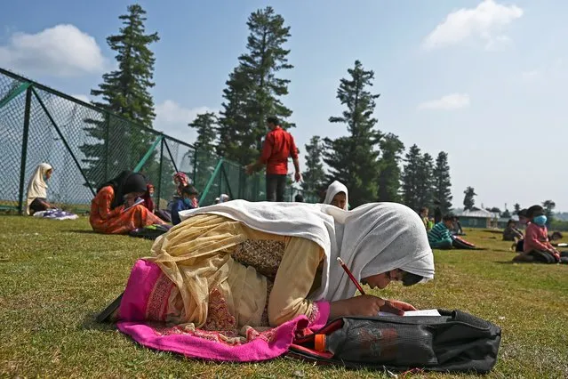 Students attend a class at their open-air school situated on top of a mountain in Doodhpathri, Indian-administered Kashmir, on July 27, 2020. Schooling in restive Kashmir has been severely disrupted by the pandemic, but also after a strict curfew was imposed almost a year ago when New Delhi stripped the Muslim-majority region of 14 million people of its semi-autonomy. (Photo by Tauseef Mustafa/AFP Photo)