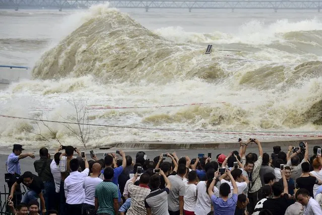 People take pictures as they watch waves caused by a tidal bore at the bank of the Qiantang River, in Hangzhou, Zhejiang province, September 30, 2015. (Photo by Reuters/Stringer)