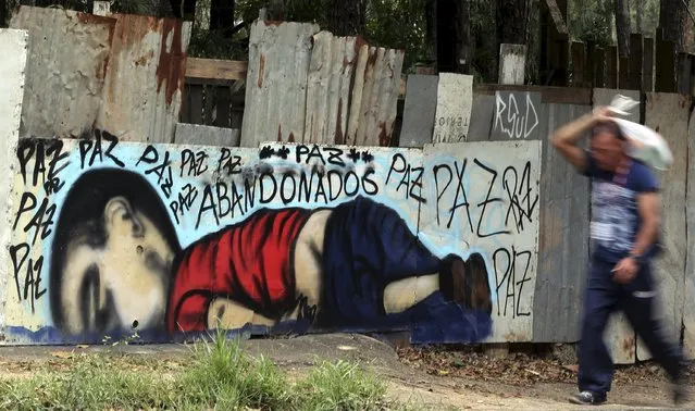 A person walks past a graffiti depicting the drowned Syrian toddler Aylan Kurdi in Sorocaba, Brazil, September 5, 2015. The graffiti reads: “Peace, peace, peace, abandoned”. (Photo by Paulo Whitaker/Reuters)