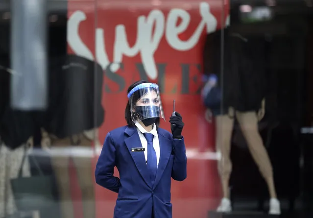 A security guard wearing a protective face shield as a precaution against coronavirus outbreak talks on her radio at Margo City shopping mall, which has been closed after a number of employees of a supermarket at the mall were tested positive for the virus, in Depok, Indonesia, Saturday, August 22, 2020. (Photo by Dita Alangkara/AP Photo)