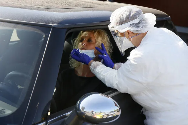 A technician collects nasal swab samples for COVID-19 at a drive-through testing centre in Wambrechies, northern France, Monday, September 21, 2020. Coronavirus infections tipped the scales again in France on Saturday with nearly 13,500 new infections in 24 hours. (Photo by Michel Spingler/AP Photo)
