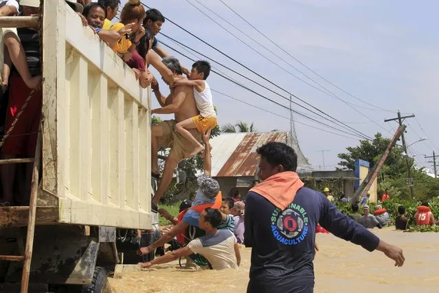 Residents climb on a truck after wading in chest-deep flood waters brought by typhoon Koppu that battered Candaba town, Pampanga province, north of Manila October 20, 2015. (Photo by Romeo Ranoco/Reuters)