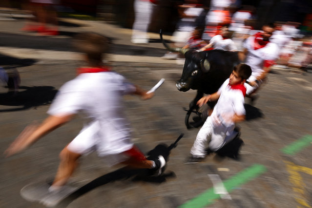 Children run next to a toy bull during the Encierro Txiki (Little Running of the Bulls) at the San Fermin festival in Pamplona, Spain, on July 11, 2025. (Photo by Albert Gea/Reuters)