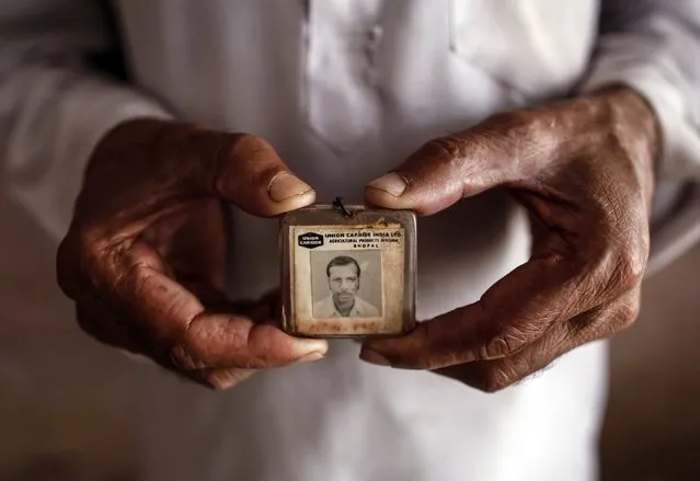 Former maintenance worker, Mohammed Yaqub, poses in his house with his old identity card from the defunct Union Carbide pesticide plant in Bhopal where he once worked November 13, 2014. (Photo by Danish Siddiqui/Reuters)