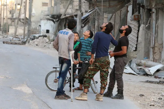 People look at the sky fearing an airstrike in the rebel-held al-Myassar neighbourhood of Aleppo, Syria, September 27, 2016. (Photo by Abdalrhman Ismail/Reuters)