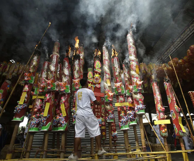 A temple worker adjusts a giant incense stick at a Chinese temple in Bangkok, Thailand, Friday, September 30, 2016. on the eve of the Vegetarian Festival. During the festival which runs from Oct. 1-9, in 2016, worshippers refrain from eating animal products over the nine days to coincide with the celebration of the nine Chinese Emperor Gods. (Photo by Sakchai Lalit/AP Photo)