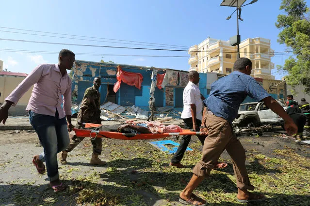 Rescuers carry a injured man on a stretcher who was injured following a explosion in front of the Blue Sky restaurant in Mogadishu, Somalia, October 1, 2016. (Photo by Feisal Omar/Reuters)