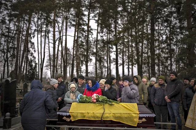 Relatives mourn next to the body of Yurii Kulyk, 27, during his funeral in Kalynivka, near Kyiv, Ukraine, Tuesday, February 21, 2023. Yurii, a civilian who was a volunteer in the armed forces of Ukraine, was killed during a rocket attack on Feb. 15 in Lyman, a city in the Donetsk region of Ukraine. (Photo by Emilio Morenatti/AP Photo)