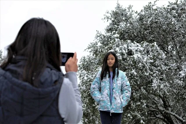 A teenager poses for a picture as snow falls on the hills around the Bay Area while a massive winter storm passes along the west coast, delivering some snow, freezing rains, and gusty winds around, near San Jose, California, U.S., February 23, 2023. (Photo by Carlos Barria/Reuters)
