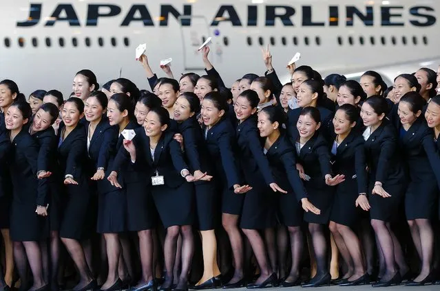 Japan Airlines new employees pose for photographs in front of a JAL aircraft during a welcoming ceremony at the company's hangar near Haneda Airport in Tokyo, Japan, on April 1, 2013. (Photo by Kiyoshi Ota/Bloomberg)